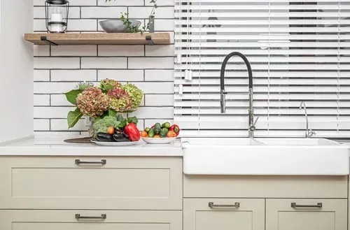 Bright kitchen with sage cabinets and fresh vegetables laid out on the counter ready for prep