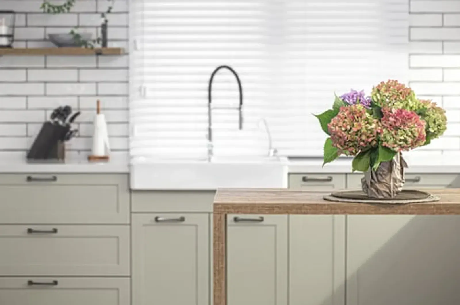 Sage green kitchen with wood countertops, fresh flowers and a clear, uncluttered surface
