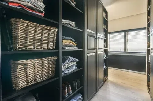 Open shelving unit with woven storage baskets and neatly folded items in a children's storage area