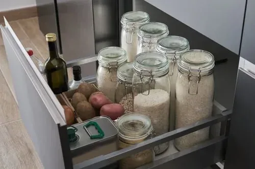 Pull-out pantry drawer organized with labeled glass jars of grains, pasta and dry goods